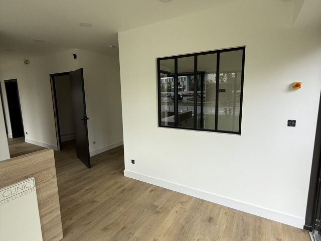 Espace d'accueil amenage de JFG Clinic avec bureau en bois et verriere